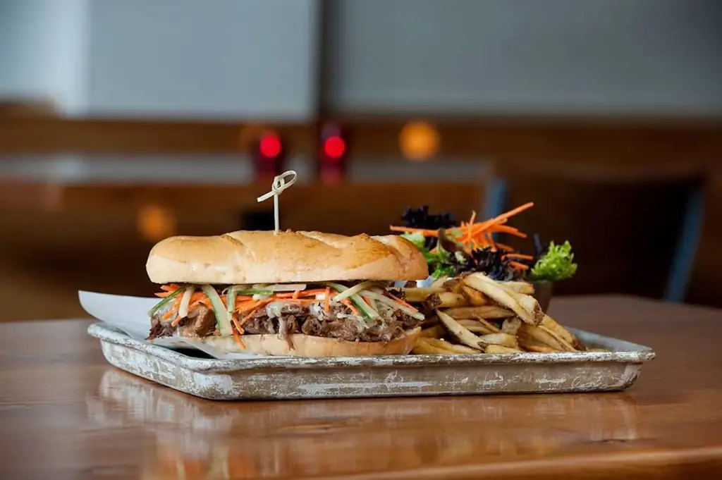 Pork and veggie sandwich with a side salad and fries